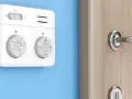 Termostato bianco su muro blu, parte di moderni sistemi di termoregolazione, con manopole per temperatura e modalità.