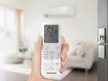 Mano che tiene un telecomando per impostare il condizionatore aria fredda su 24°C.