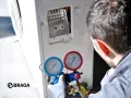 Tecnico controlla i manometri collegati al condizionatore. Se manca il gas nel condizionatore, l'efficienza diminuisce e potrebbe non raffreddare.