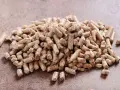 Un mucchio di pellet di abete rosso o bianco, combustibile ecologico per il riscaldamento domestico, su una superficie ruvida.