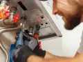 Tecnico con guanti lavora su caldaia, forse per risolvere problema di acqua calda sporca.