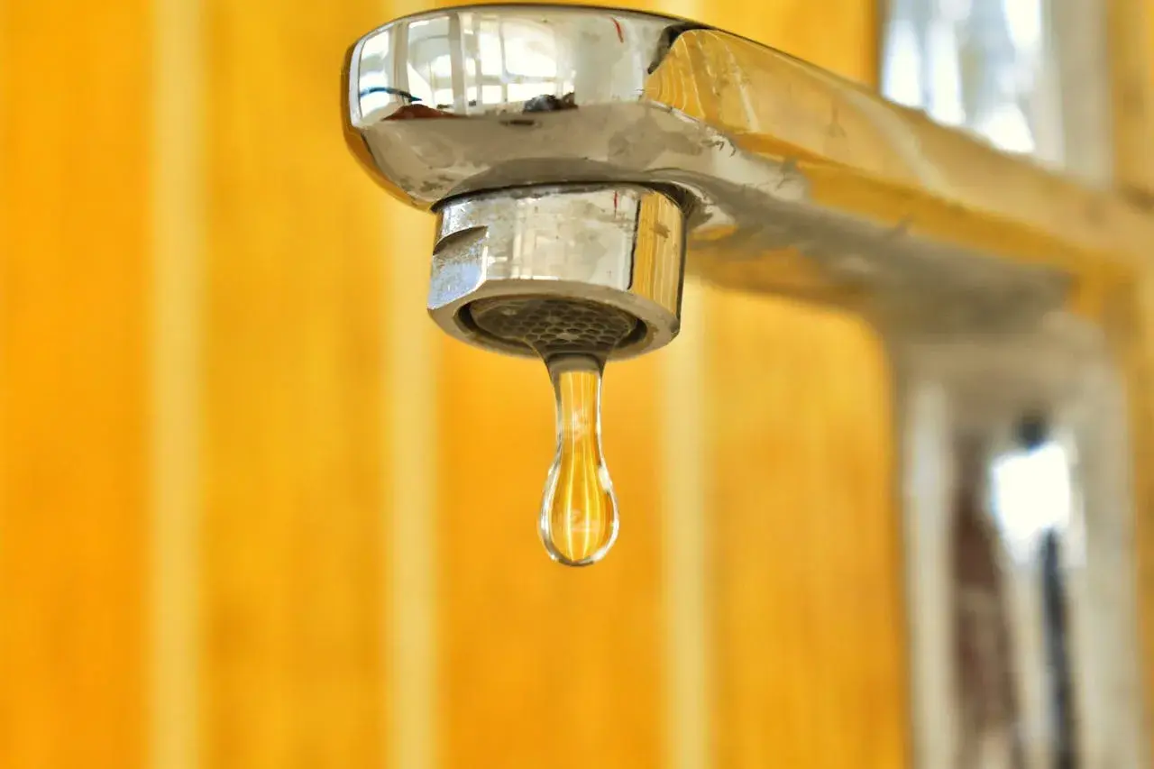 Goccia d'acqua fredda dal rubinetto cromato. La caldaia non esce acqua calda, un problema comune in casa.