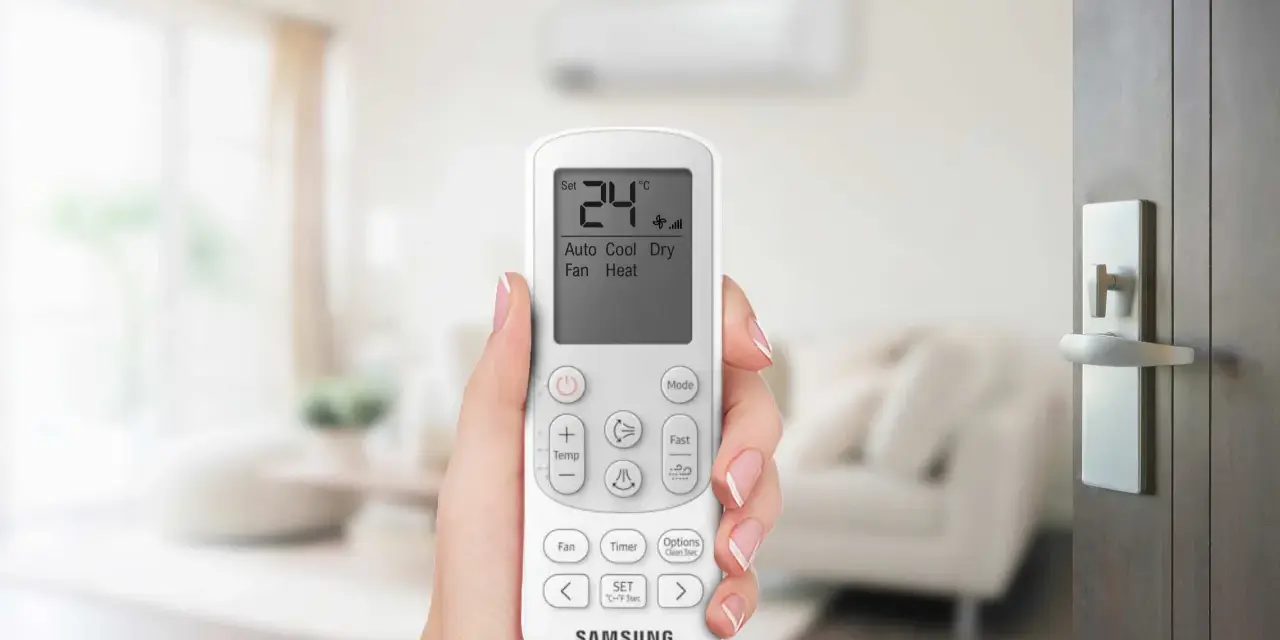 Mano che tiene un telecomando per impostare il condizionatore aria fredda su 24°C.