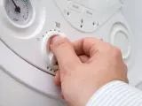 Mano che regola la manopola per impostare la temperatura acqua termosifoni. Si vede un manometro.