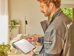 Tecnico Daikin controlla sul tablet quanto dura una pompa di calore, analizzando dati per ottimizzare l'efficienza.