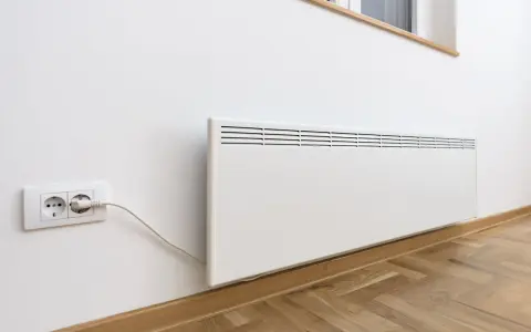 Termoconvettori bianchi montati a parete, uno collegato a una presa elettrica, pronti a riscaldare l'ambiente.