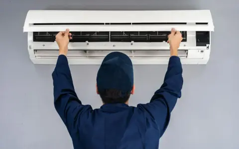 Tecnico controlla un condizionatore che non raffredda, aprendo il pannello frontale per ispezionare i filtri.