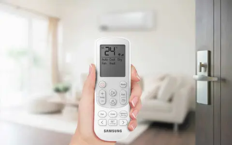 Mano che tiene un telecomando per impostare il condizionatore aria fredda su 24°C.
