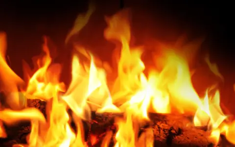 Fiamme vivaci danzano su legna ardente. La stufa a pellet si accende da sola, creando un'atmosfera calda e accogliente.