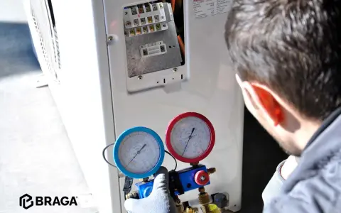 Tecnico controlla i manometri collegati al condizionatore. Se manca il gas nel condizionatore, l'efficienza diminuisce e potrebbe non raffreddare.