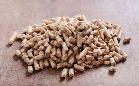 Un mucchio di pellet di abete rosso o bianco, combustibile ecologico per il riscaldamento domestico, su una superficie ruvida.