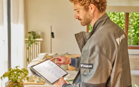 Tecnico Daikin controlla sul tablet quanto dura una pompa di calore, analizzando dati per ottimizzare l'efficienza.
