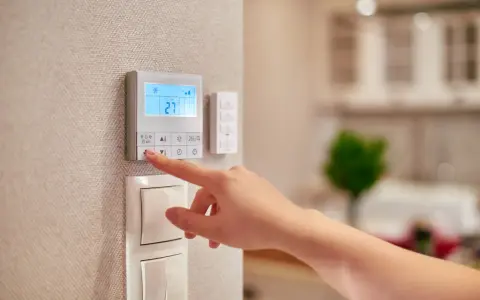 Dito si vede come funziona un termostato manuale: una mano preme un pulsante per regolare la temperatura.