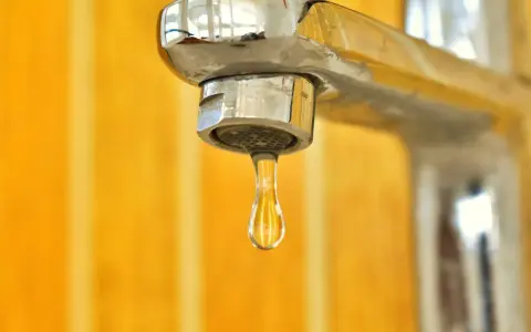 Goccia d'acqua fredda dal rubinetto cromato. La caldaia non esce acqua calda, un problema comune in casa.