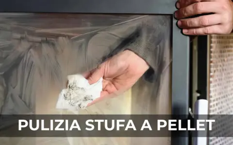Mano che pulisce il vetro di una stufa a pellet con un panno sporco di fuliggine.