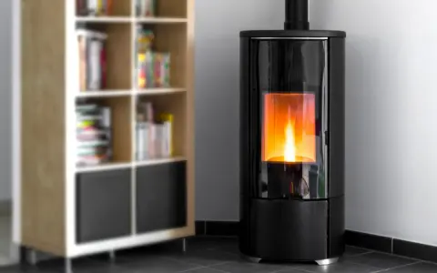 Stufa a pellet moderna con fiamma viva, ideale per dormire con la stufa a pellet accesa in un ambiente accogliente, accanto a una libreria.