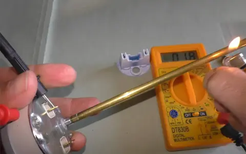 Come controllare un termostato con il tester: un multimetro digitale misura la resistenza di un componente metallico riscaldato.