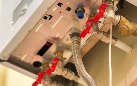 Dettaglio di una caldaia con valvole rosse e tubi. Monitorare la pressione massima caldaia è fondamentale per la sicurezza.