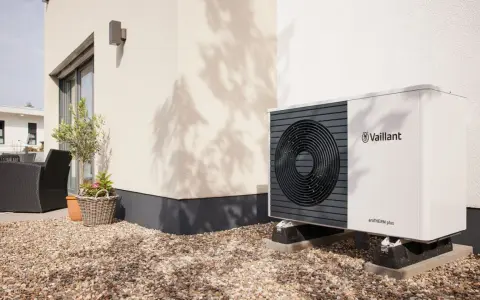 Unità esterna Vaillant per raffrescamento con termosifoni, posizionata su ghiaia vicino a una casa moderna.