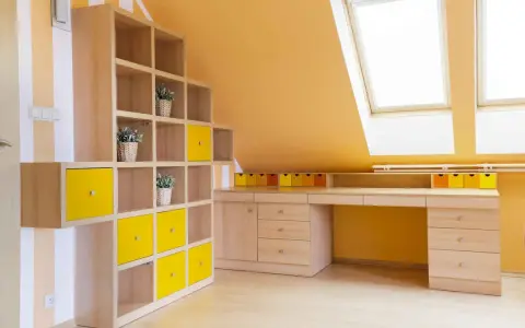 Luminosa mansarda con pareti arancioni e mobili in legno chiaro. Le idee colori pareti mansarda sono valorizzate da cubi contenitori gialli e un'ampia scrivania.