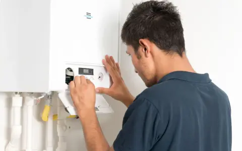 Tecnico effettua il collaudo caldaia nuova, regolando i comandi per un funzionamento ottimale.