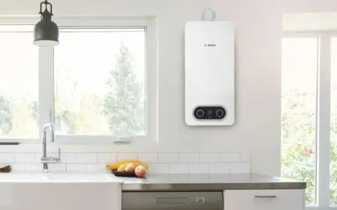 Scaldabagno a gas Bosch bianco, con pannello di controllo digitale, montato a parete in una cucina moderna.