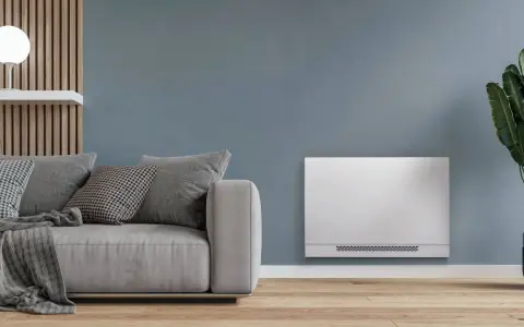 Soggiorno moderno con divano grigio e un elegante termoconvettore ad acqua al posto del termosifone, che diffonde calore in modo discreto.