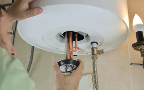 Un tecnico ripara uno scaldabagno che attacca e stacca, mostrando le resistenze in rame.