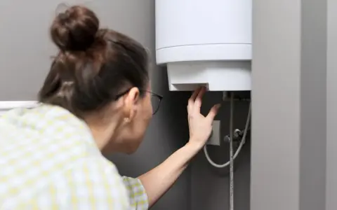Donna controlla il suo scaldabagno da 50 litri, verificando il tempo di riscaldamento.