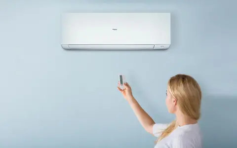 Donna con telecomando regola il condizionatore Haier. Il suo significato è il comfort climatico.