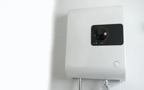 Scaldabagno elettrico istantaneo: pro e contro. Un dispositivo bianco montato a parete con un quadrante nero e indicatori luminosi.