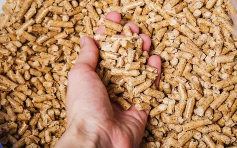 Mano che afferra pellet di legno. Un sacco di pellet di legno ha un peso variabile, ma solitamente si aggira sui 15 kg.