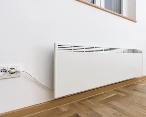 Termoconvettori bianchi montati a parete, uno collegato a una presa elettrica, pronti a riscaldare l'ambiente.