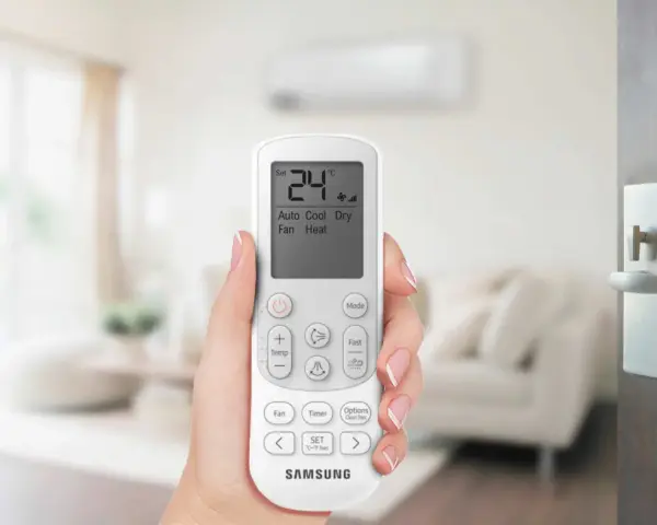 Mano che tiene un telecomando per impostare il condizionatore aria fredda su 24°C.