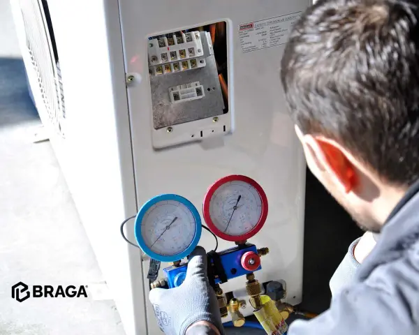 Tecnico controlla i manometri collegati al condizionatore. Se manca il gas nel condizionatore, l'efficienza diminuisce e potrebbe non raffreddare.