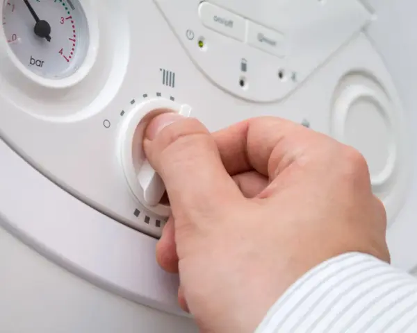 Mano che gira la manopola per alzare la temperatura della caldaia. Si vede il quadrante della pressione.
