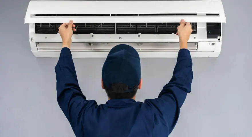 Tecnico controlla un condizionatore che non raffredda, aprendo il pannello frontale per ispezionare i filtri.