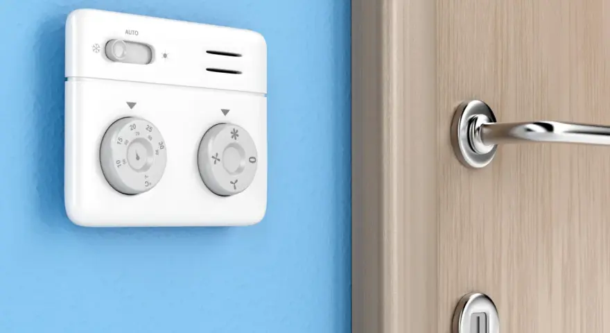 Termostato bianco su muro blu, parte di moderni sistemi di termoregolazione, con manopole per temperatura e modalità.