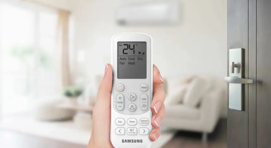 Mano che tiene un telecomando per impostare il condizionatore aria fredda su 24°C.