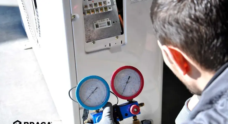 Tecnico controlla i manometri collegati al condizionatore. Se manca il gas nel condizionatore, l'efficienza diminuisce e potrebbe non raffreddare.