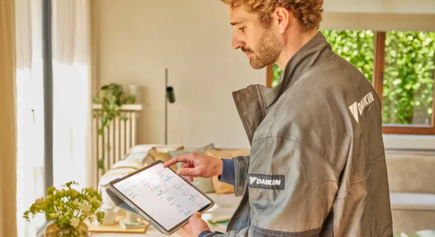Tecnico Daikin controlla sul tablet quanto dura una pompa di calore, analizzando dati per ottimizzare l'efficienza.