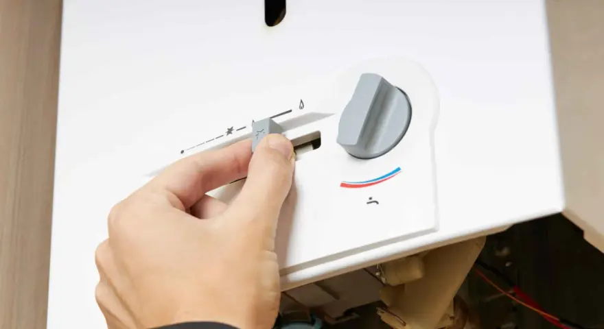 Mano regola la manopola di uno scaldabagno a gas Bosch, forse per risolvere problemi di funzionamento.