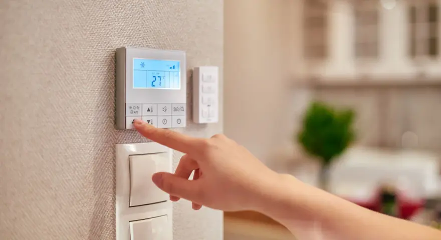 Dito si vede come funziona un termostato manuale: una mano preme un pulsante per regolare la temperatura.