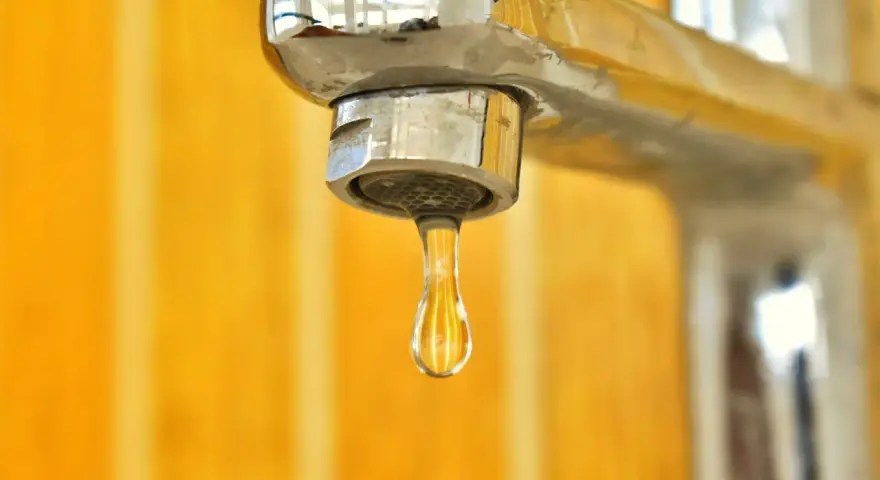 Goccia d'acqua fredda dal rubinetto cromato. La caldaia non esce acqua calda, un problema comune in casa.