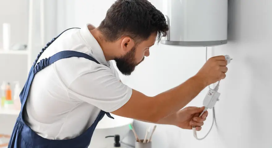 Tecnico con tuta blu controlla la caldaia. La manutenzione caldaia a chi spetta? Al tecnico specializzato, per la sicurezza di tutti.