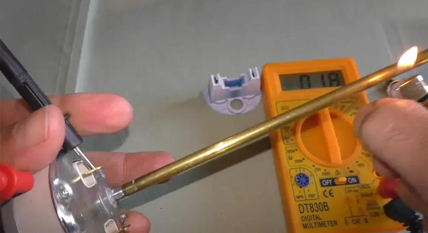 Come controllare un termostato con il tester: un multimetro digitale misura la resistenza di un componente metallico riscaldato.
