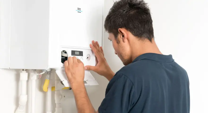 Tecnico effettua il collaudo caldaia nuova, regolando i comandi per un funzionamento ottimale.