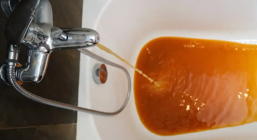 Rubinetto che eroga acqua troppo calda, di colore arancione, nella vasca da bagno.