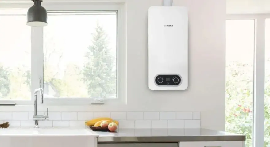 Scaldabagno a gas Bosch bianco, con pannello di controllo digitale, montato a parete in una cucina moderna.