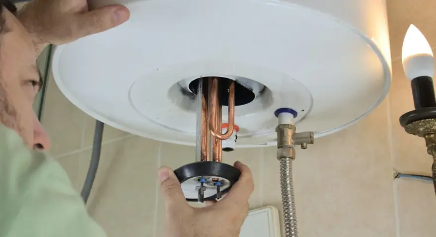 Un tecnico ripara uno scaldabagno che attacca e stacca, mostrando le resistenze in rame.